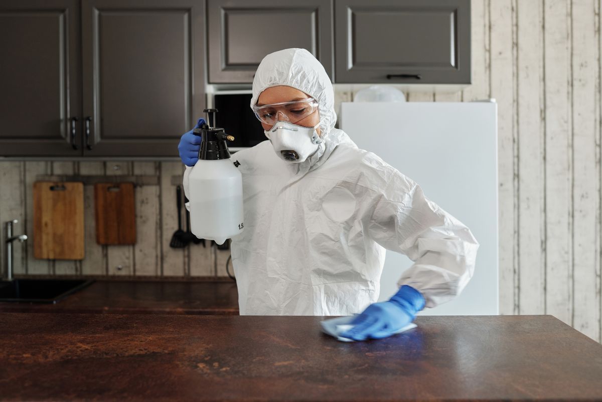 Technician in protective suit disinfecting a surface